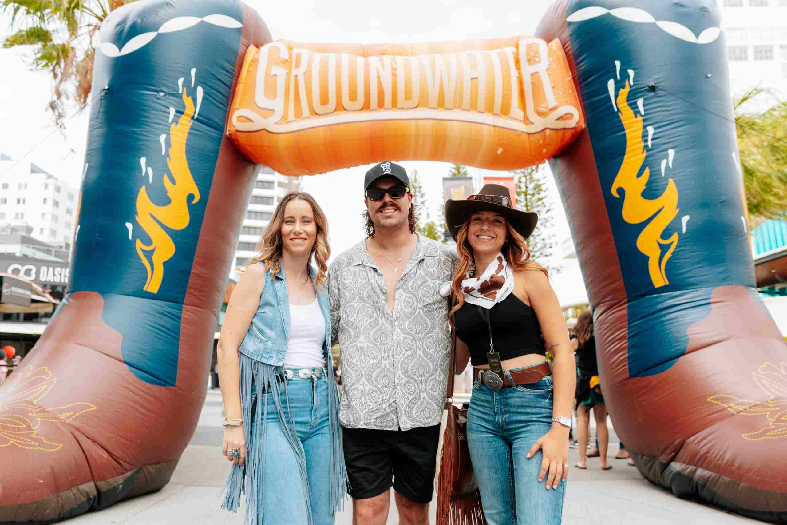 Festival-goers at the Broadbeach Country Music Festival 2025 posing under the Groundwater entrance arch.